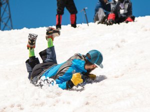 boy practicing with an ice ax to self arrest on snow