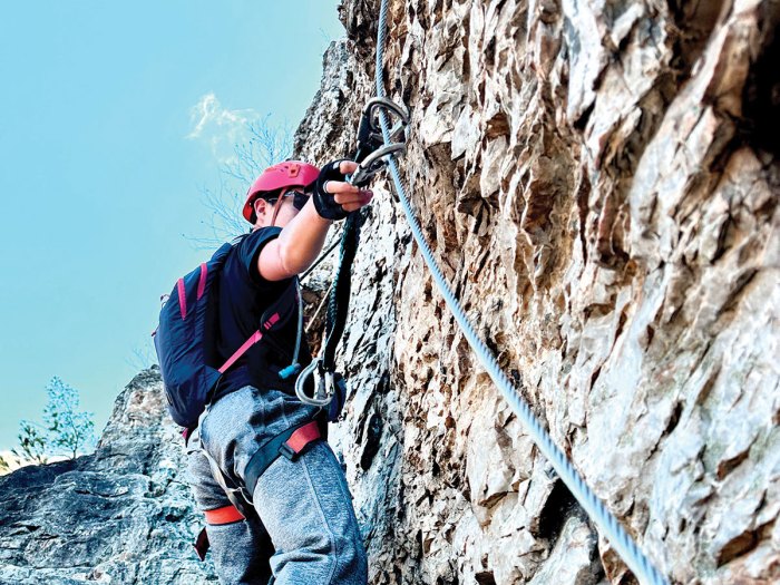 Scout attaches a carabiner to the belay cable on the via ferrata route